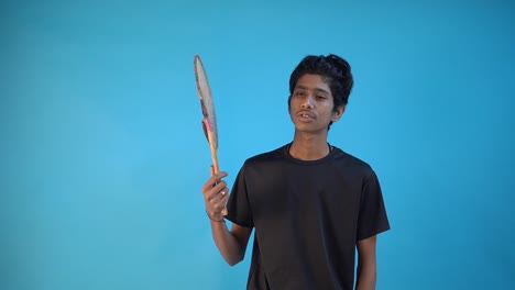Junger-Indischer-Junge,-Der-Sich-Zu-Hause-Mit-Handgefertigtem-Jutefächer-Im-Blauen-Hintergrundstudio-Entspannt