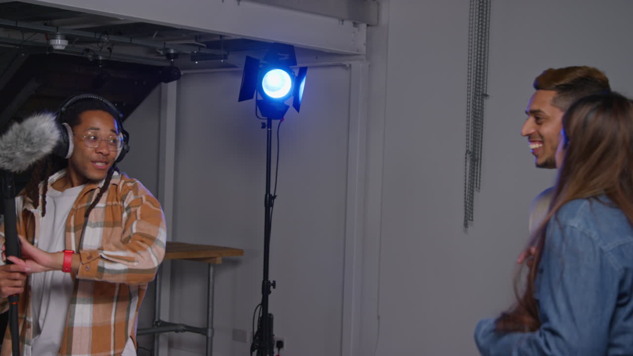 A group of people are in a music recording studio, with a microphone and recording equipment