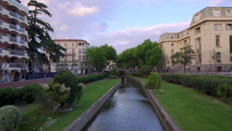 Panning-shot-from-a-bright-over-a-canal-in-Perpignan-city-center-on-a-summers-day,-Occitanie,-France