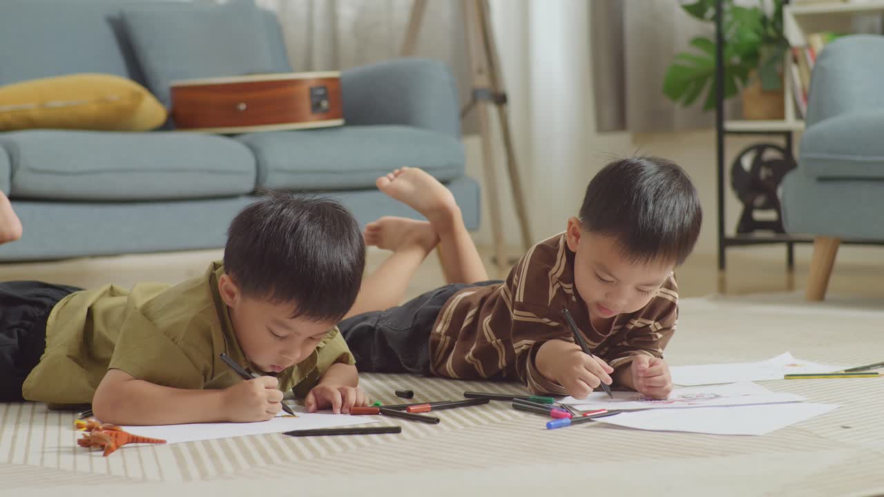 집에서 함께 그림을 그리는 바닥에 누워있는 아시아 아이들의 클로즈업