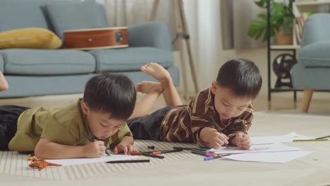 close up of asian kids lying on the floor drawing together at home