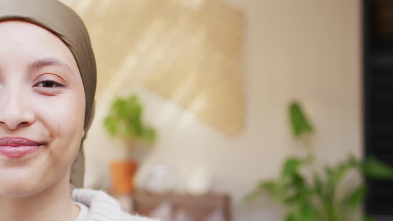 카메라에 미소 짓는 갈색 히자브를 입은 행복한 두 인종 여성의 반 얼굴의 비디오 초상화, 복사 공간