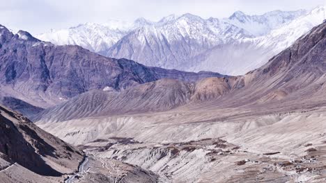aerial drone shot displaying a vehicle climbing steep inclines on ladakh’s remote mountain roads.