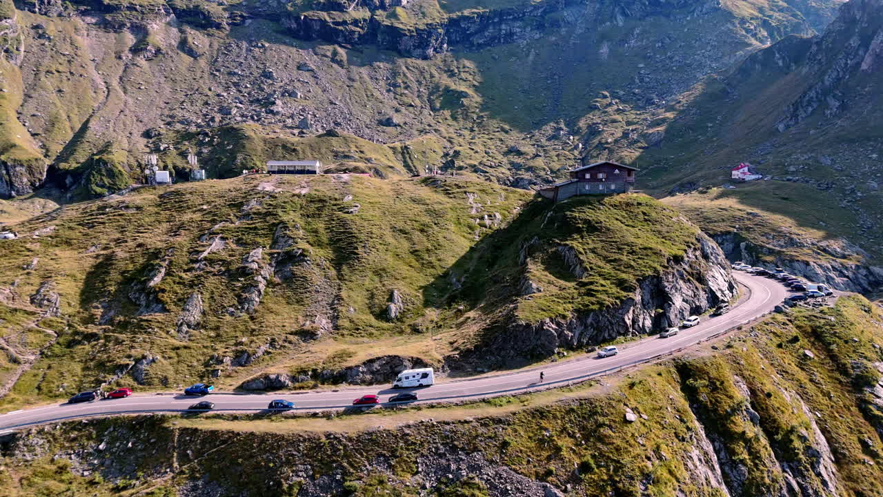 Scenic mountain road with cars winding through lush green hills