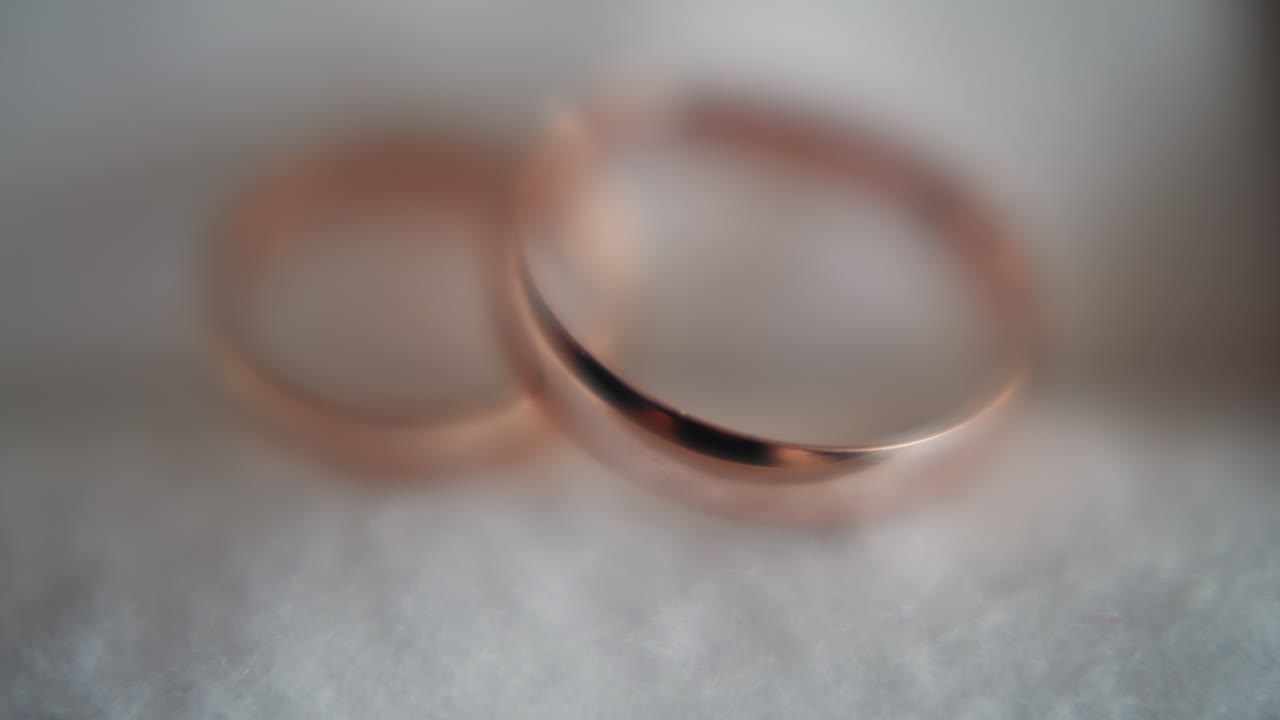 Gold wedding rings pair on soft white fabric extreme closeup