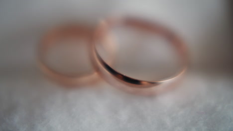 gold wedding rings pair on soft white fabric extreme closeup