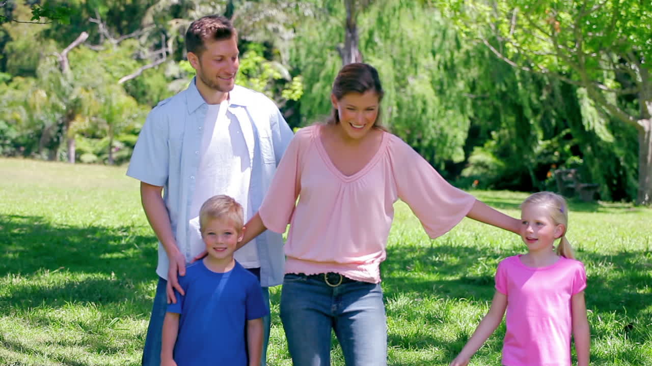 niño pateando una pelota mientras camina en la hierba con su familia