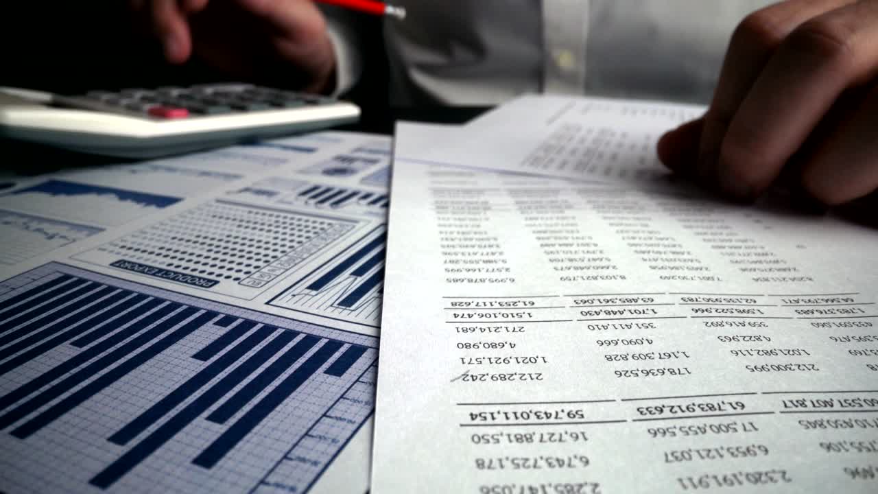 Accountant analyzing business marketing data on paper dashboard at office table.
