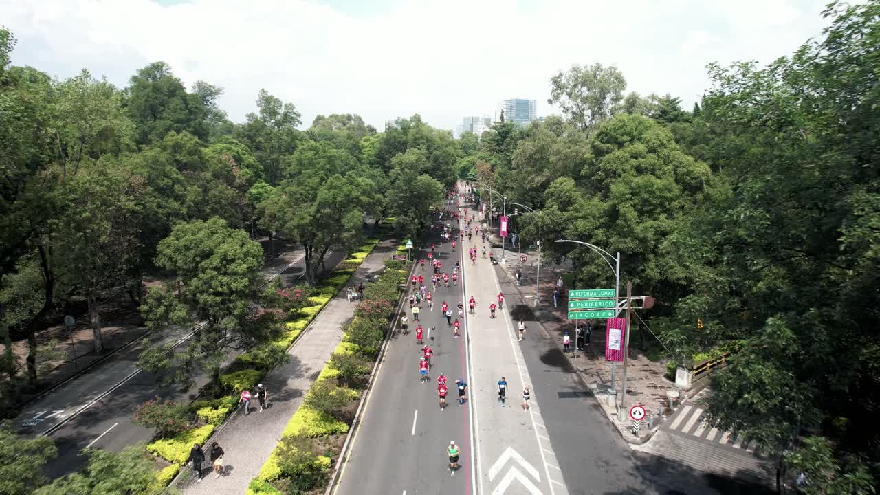 disparo rápido de dron hacia atrás de los corredores de maratón de la ciudad que pasan por la avenida refoma