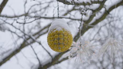 照亮悬挂在雪覆盖的户外树枝上的装饰品