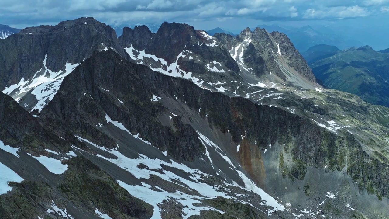 Epic aerial tilt-up reveal of rugged granite peaks and snowy ridges in Chamonix, France. Cinematic drone footage of the high-altitude Mont Blanc massif on a clear winter day