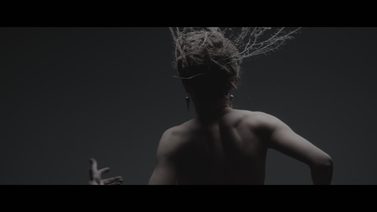 A woman dressed as mother nature moves slowly in a dance-like motion