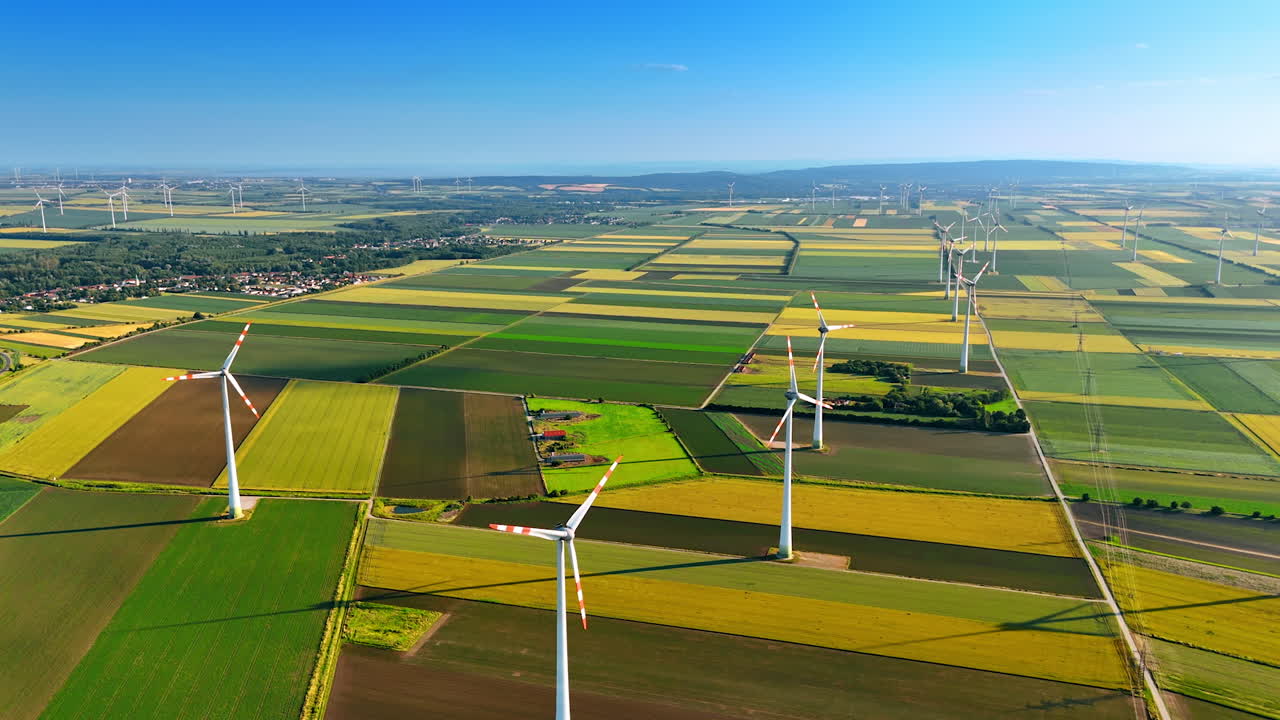 Turbines produce clean energy. Wind turbines turn in green fields under a clear blue sky, highlighting renewable energy in a rural setting