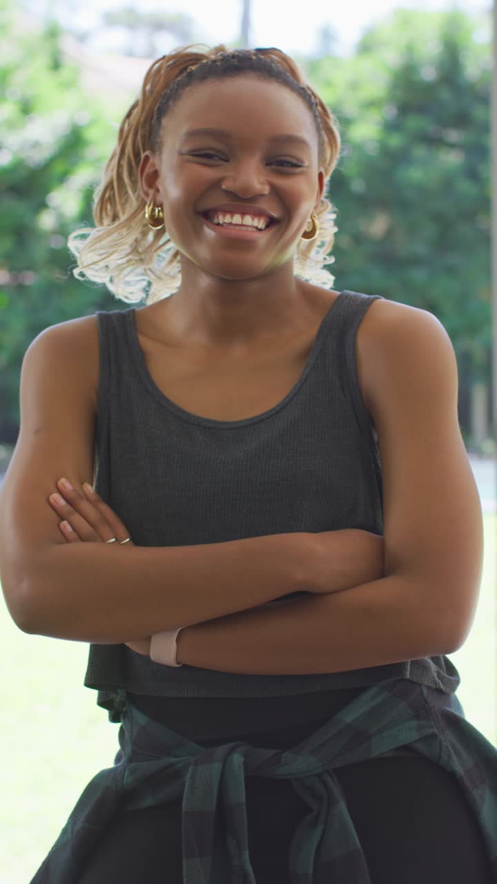 Vídeo vertical: Mulher afro-americana adulta sorrindo e rindo na porta, vestindo flanela e relógio.