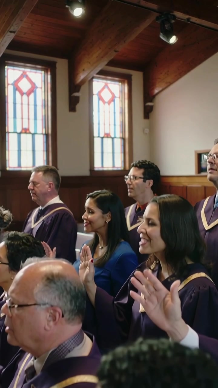 Vertical video: Camera panning choir singing and praising at chapel, purple robes, stained glass