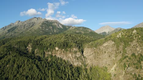 aerial dolly out rising over mountains covered in pine tree forest and corbata blanca waterfall in background, patagonia argentina