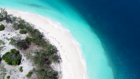 uninhabited, remote, idyllic tropical island paradise with curved white sandy beach, shallow crystal clear water and deep blue ocean on jaco island, timor leste