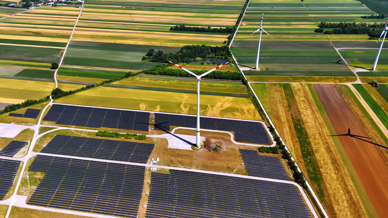 Vast fields in the countryside are used for production of renewable energy. Aerial perspective on the wind turbines and solar panels