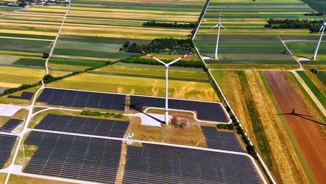 vast fields in the countryside are used for production of renewable energy. aerial perspective on the wind turbines and solar panels