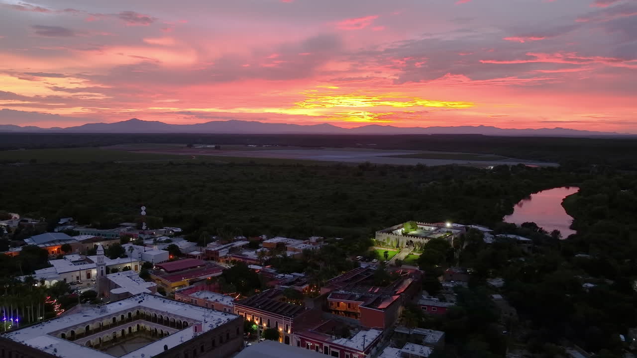 Vista aérea hacia atrás sobre la iluminada ciudad de El Fuerte, atardecer en México