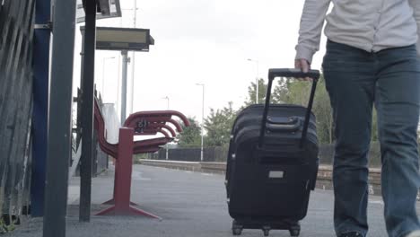 Woman-wheels-suitcase-on-train-platform-towards-camera-wide-shot