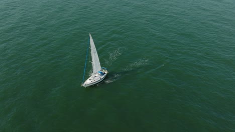 Vista-Aérea-De-Un-Velero-Blanco-En-El-Tranquilo-Mar-Báltico,-Yate-De-Vela-Blanco-En-Medio-Del-Mar-Sin-Límites,-Día-Soleado-De-Verano,-Tiro-Amplio-Moviéndose-Hacia-Atrás,-Inclinado-Hacia-Arriba