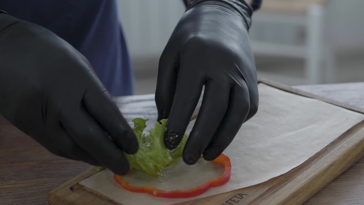 шеф-повар в черных кулинарных перчатках кладет свежие овощи, мясо на барбекю и запеченный картофель на питовый хлеб на доске,