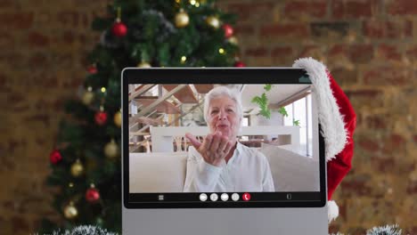 mujer mayor caucásica feliz en videollamada en el monitor de la computadora, con árbol de navidad