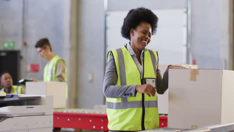 portrait of african american female worker wearing safety suit and smiling in warehouse