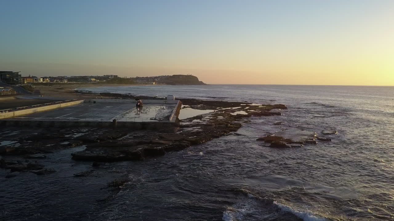 Bassenget ved Mereweather Ocean Baths blir rengjort av traktor ved soloppgang