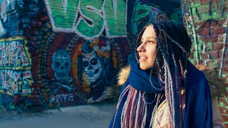 woman with colorful braids in front of graffiti wall