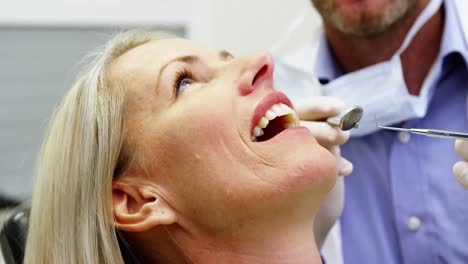 Dentist-examining-a-female-patient-with-dental-tools