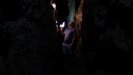 Man exploring a dark cave with a flashlight
