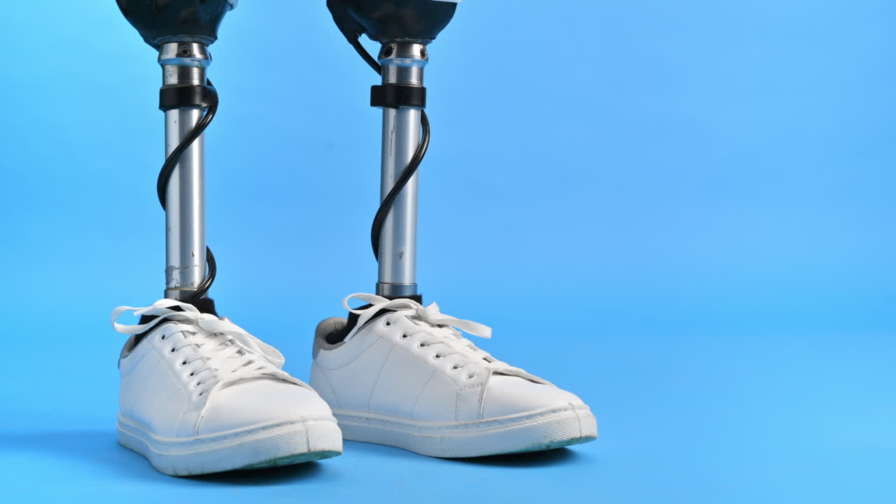 View of a man with prosthetic legs and white sneakers standing against a blue background