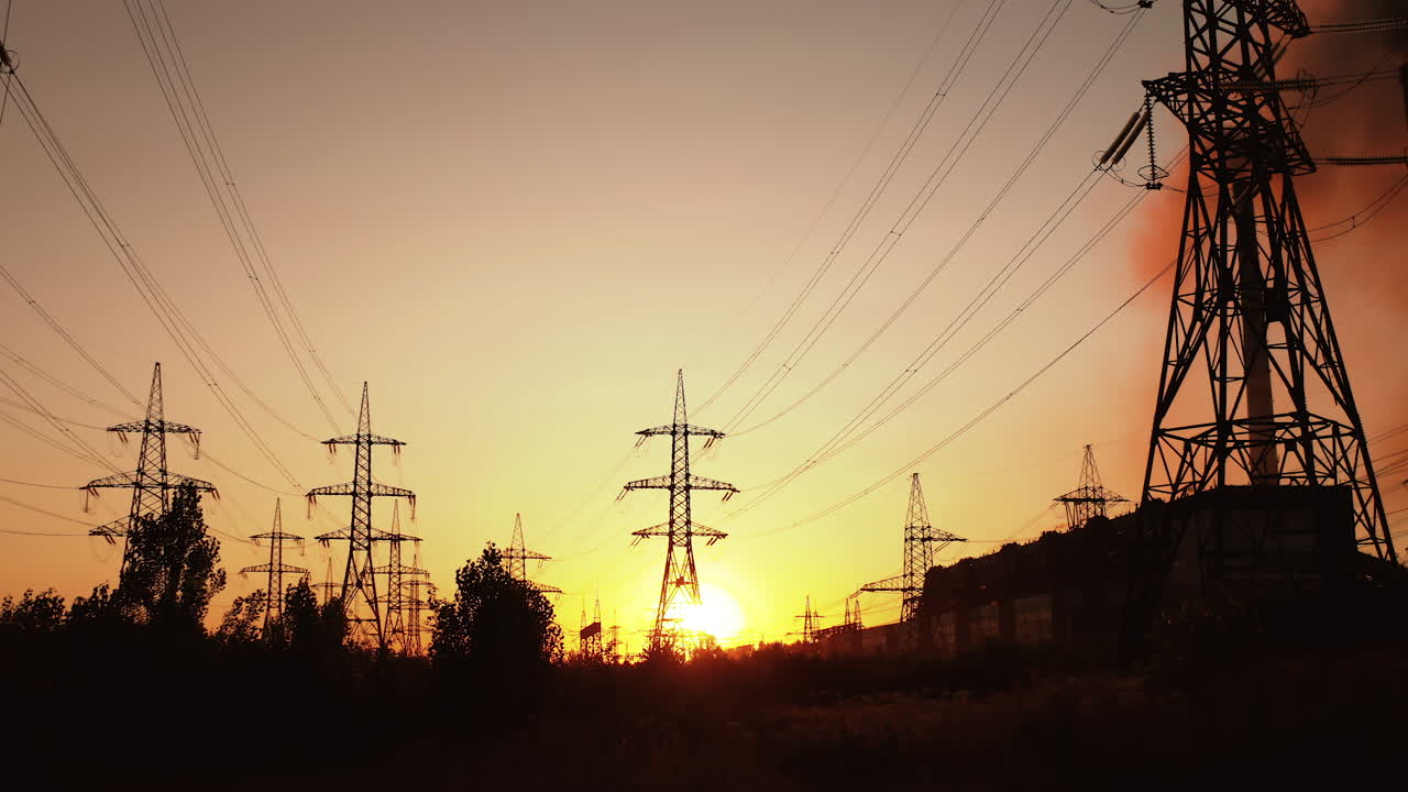 High voltage towers with sunset. Silhouette of columns and high voltage wires in the power supply station