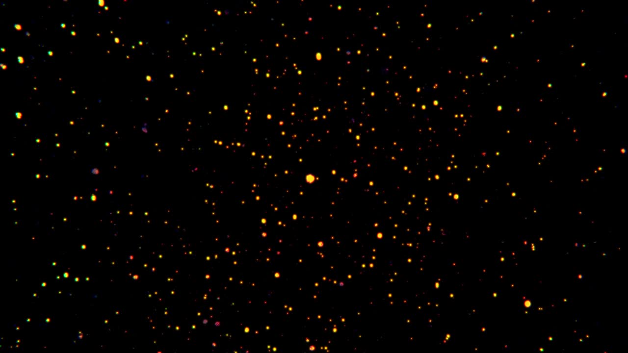 Particelle luminose fluttuano nell'aria su sfondo nero, polvere scintillante di glitter.