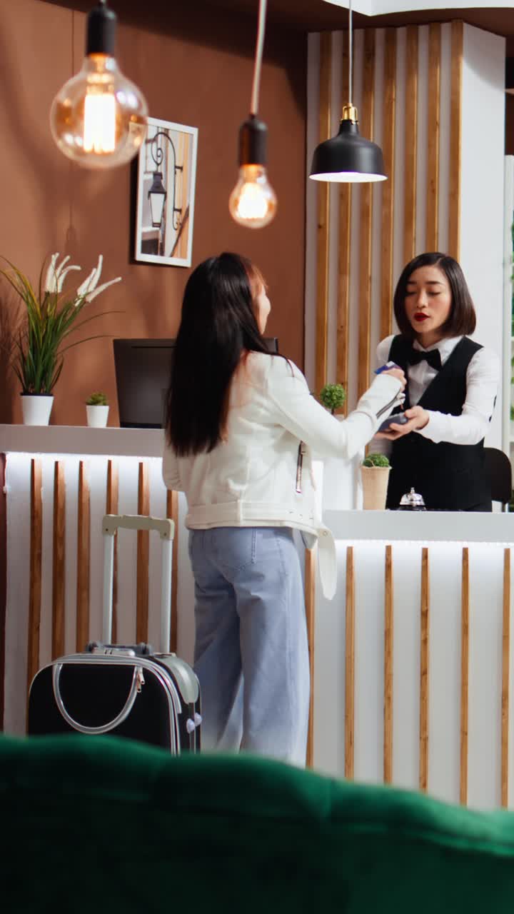 Video verticale di un ospite di un hotel che paga con la carta al terminale POS durante il check-in