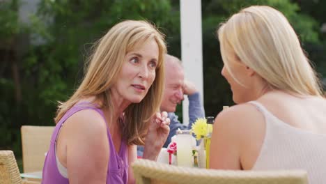 senior woman talking to young woman while having lunch outdoors