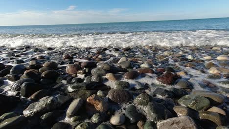 Das-Meer-Ist-Sichtbar,-Mit-Sanften-Wellen,-Die-Sich-Dem-Ufer-Unter-Einem-Klaren-Himmel-Nähern