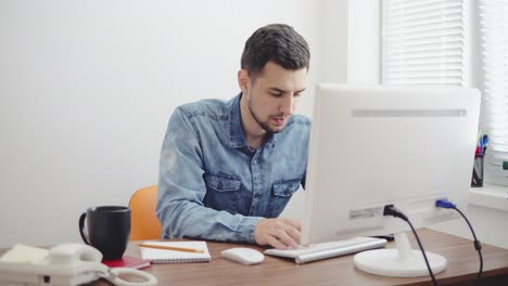 Joven-Empresario-Trabajando-En-Equipo-En-La-Oficina-Moderna-Y-Elegante.-Computadora,-Teléfono-Y-Taza-Sobre-La-Mesa.-Filmado-En-4k