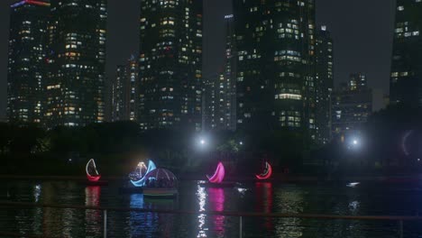 Hermosa-Vista-Romántica-Del-Parque-Nocturno-Con-Río-En-Las-Luces-De-La-Ciudad-Y-Barcos-Vista-De-ángulo-Alto-A-Rascacielos-Y-Edificios-Altos