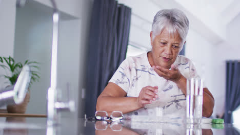 Mujer-Birracial-Mayor-Con-Un-Vaso-De-Agua-Tomando-Pastillas