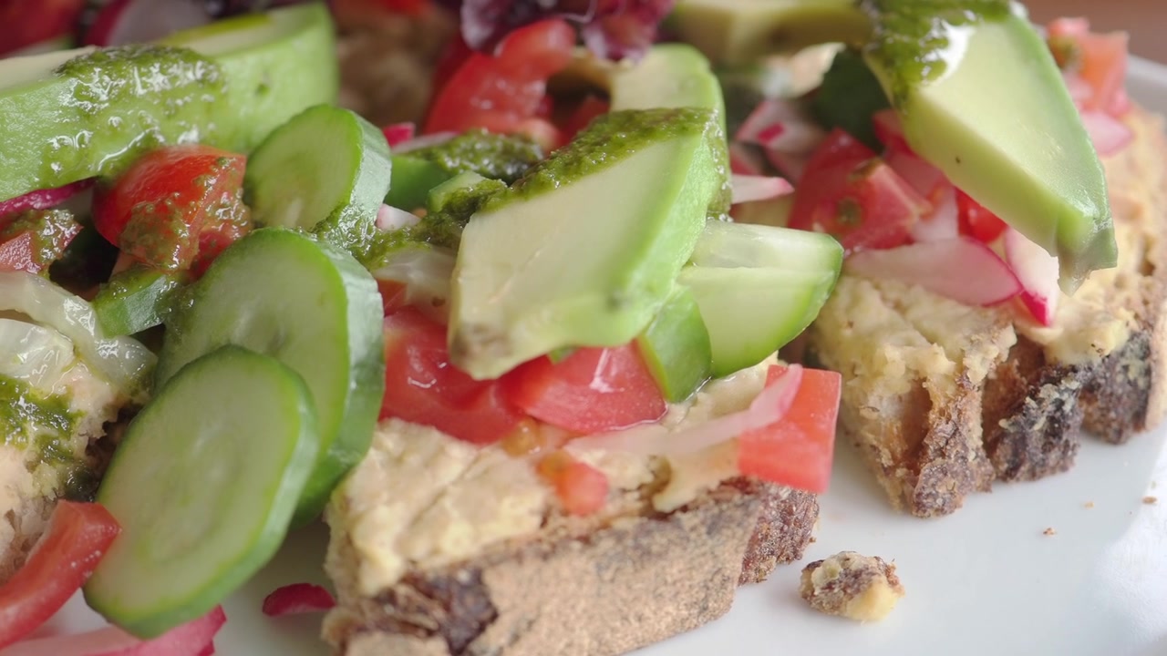 Primo piano di toast con avocado fresco e verdure su un piatto bianco