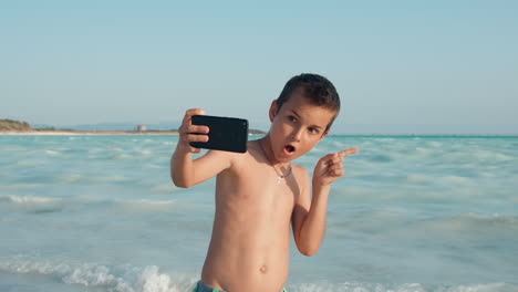 Smiling-guy-enjoying-summer-holiday-at-seaside.-Happy-boy-grimacing-at-beach.