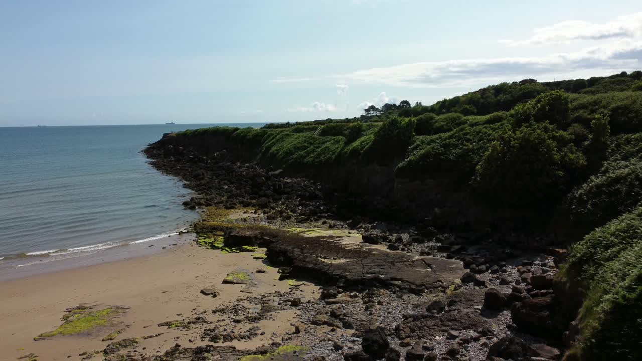 Traeth Lligwy idyllic rocky coast shoreline aerial view descending to eroded rocky beach cliffs edge