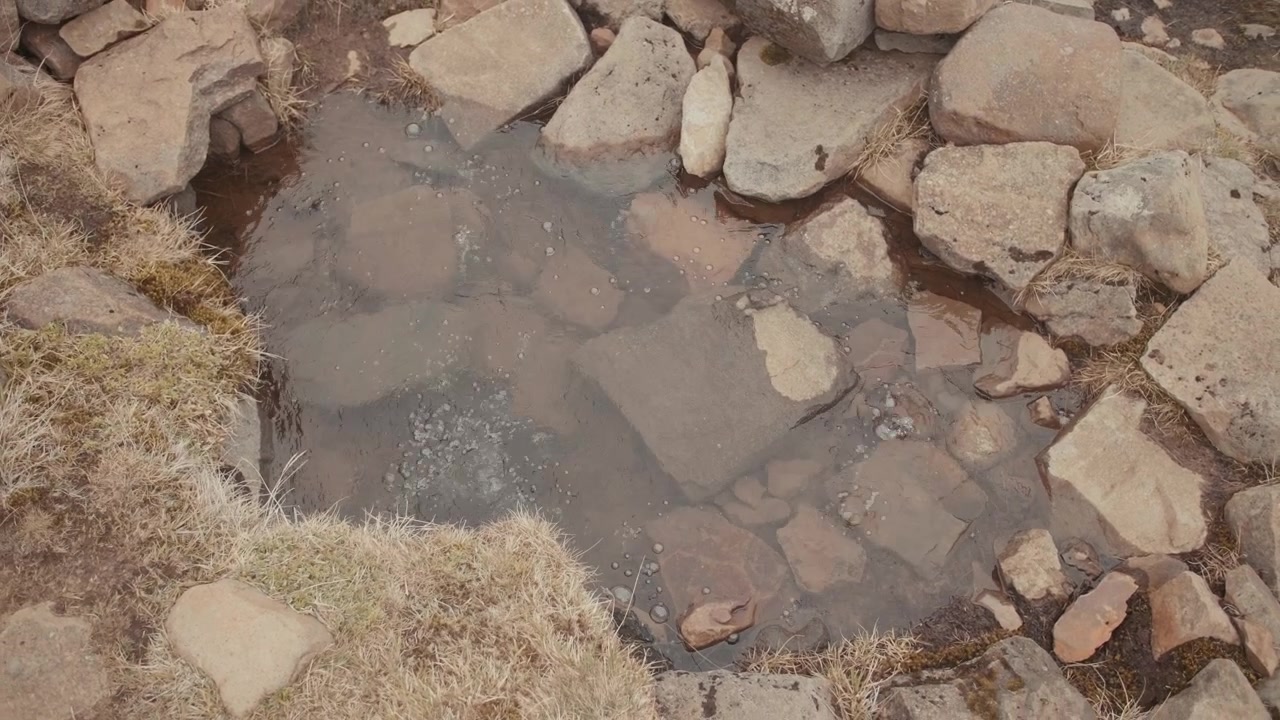 Primo piano di acqua geotermica ribollente in una pozza rocciosa.