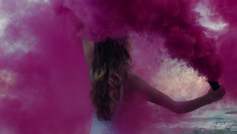 beautiful-woman-waving-pink-smoke-grenade-dancing-on-beach-in-early-morning-celebrating-creative-freedom