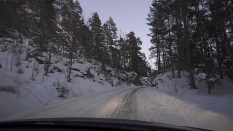 car driving on slippery road lined with frosted trees in winter