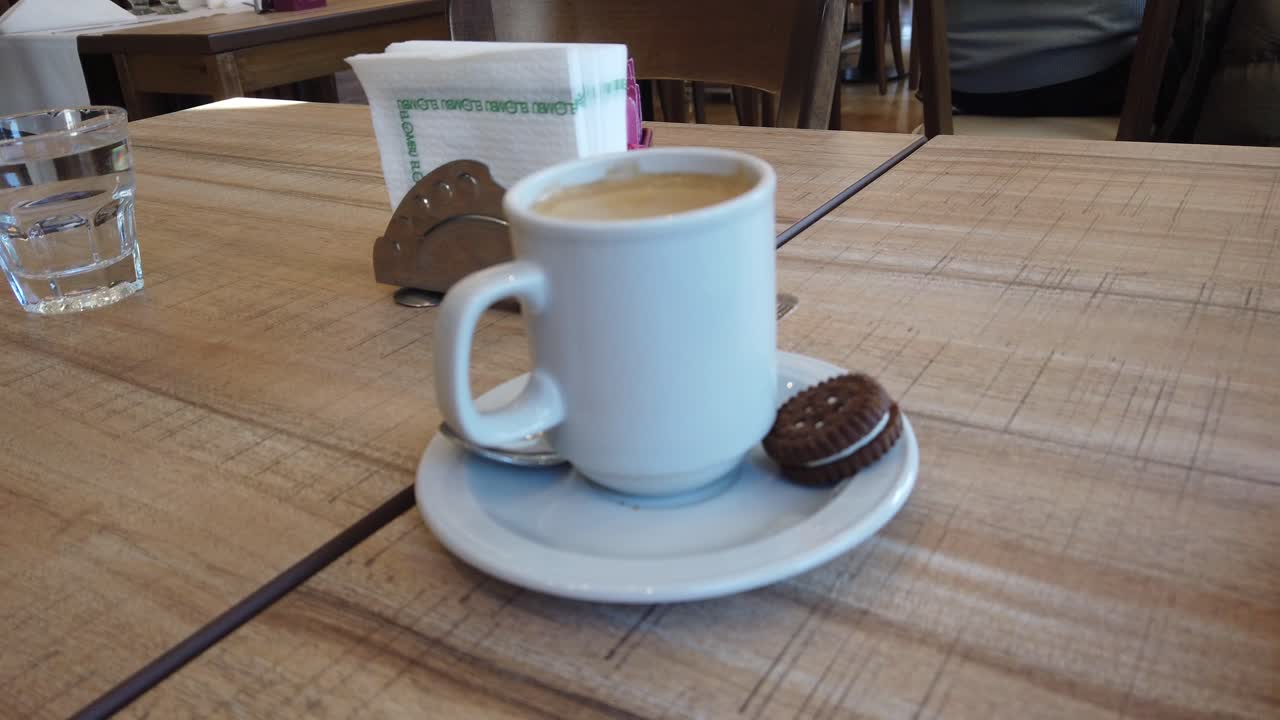 Close up of an espresso coffee cup served with a sweet chocolate cookie ready to drink in an Italian style table