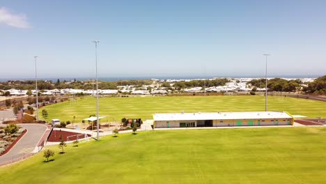 Sportplatz-Mit-Gebäude,-Flutlichter-Mit-Blauem-Himmel-Und-Meereshintergrund,-Luftaufnahme-Von-Perth,-Australien